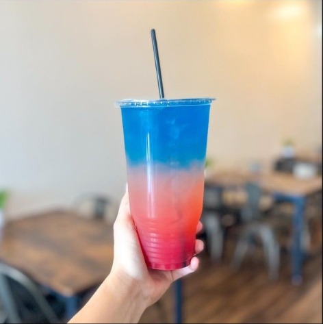 A blue-to-red layered loaded tea held up inside the shop.