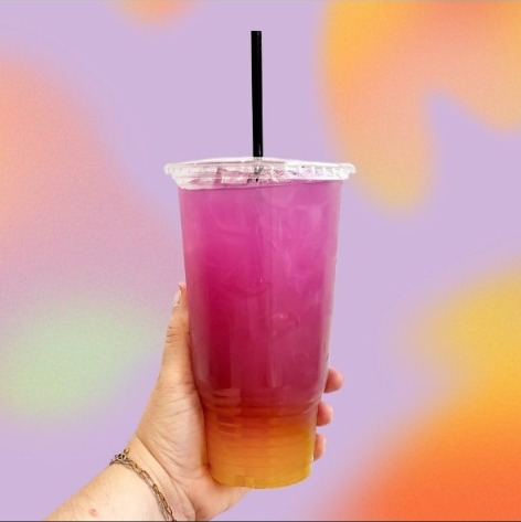 A pink-to-orange layered loaded tea held against a holographic backdrop.